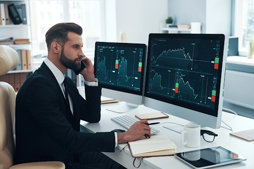 businessman-analyzing-data-on-the-stock-market-and-talking-on-the-phone-in-the-office – PU Prime | More Than Trading businessman analyzing data on the stock market and talking on the phone in the office